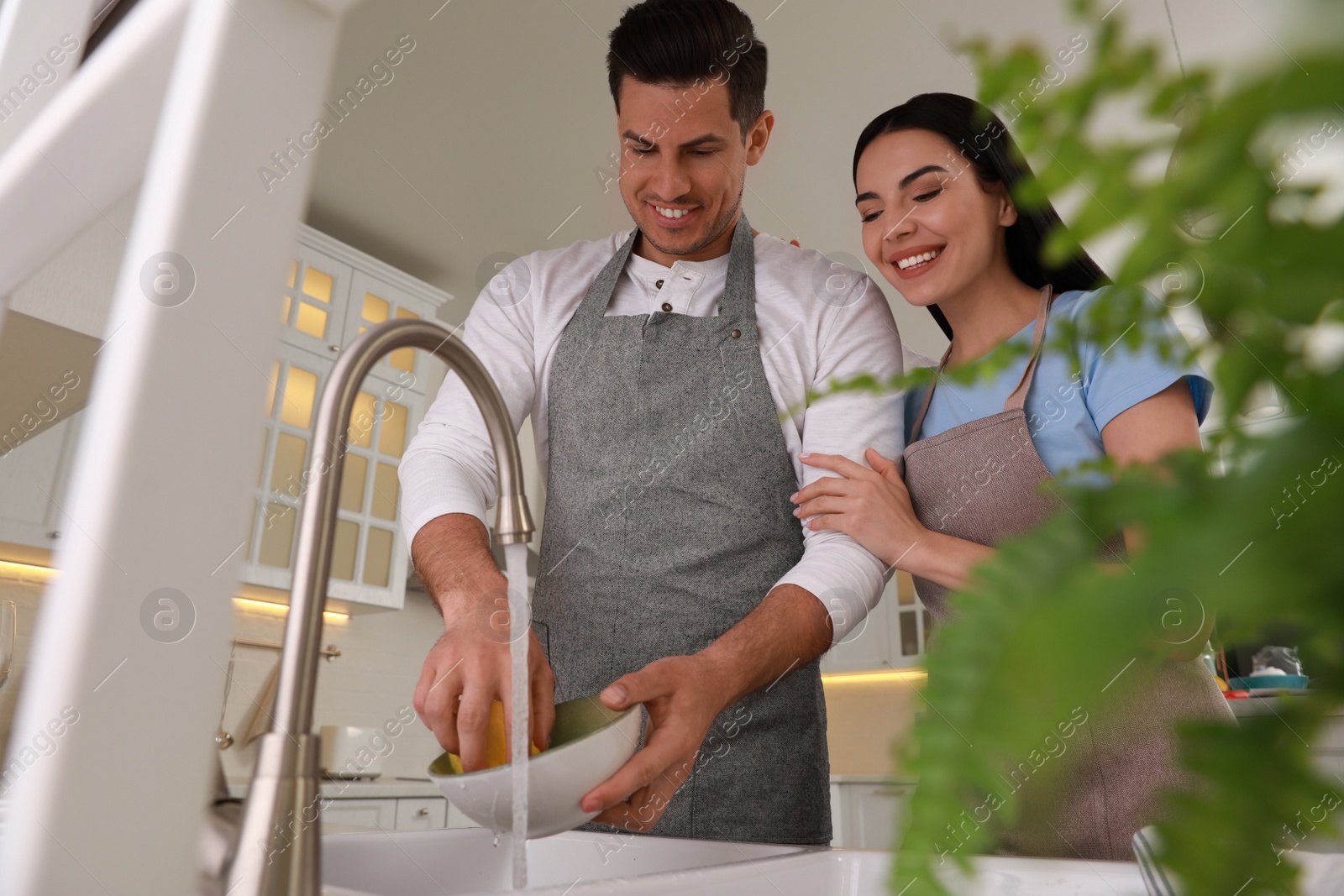 Photo of Happy lovely couple washing dishes in kitchen