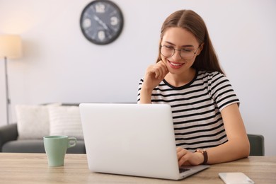 Photo of Happy young woman with laptop at table indoors