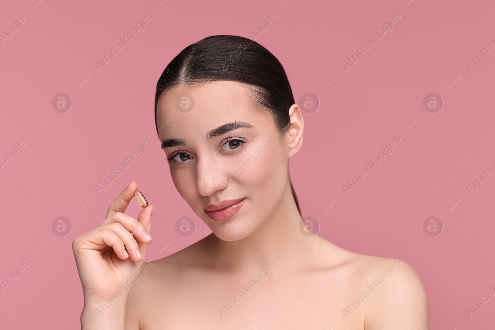 Photo of Beautiful young woman with vitamin pill on pink background