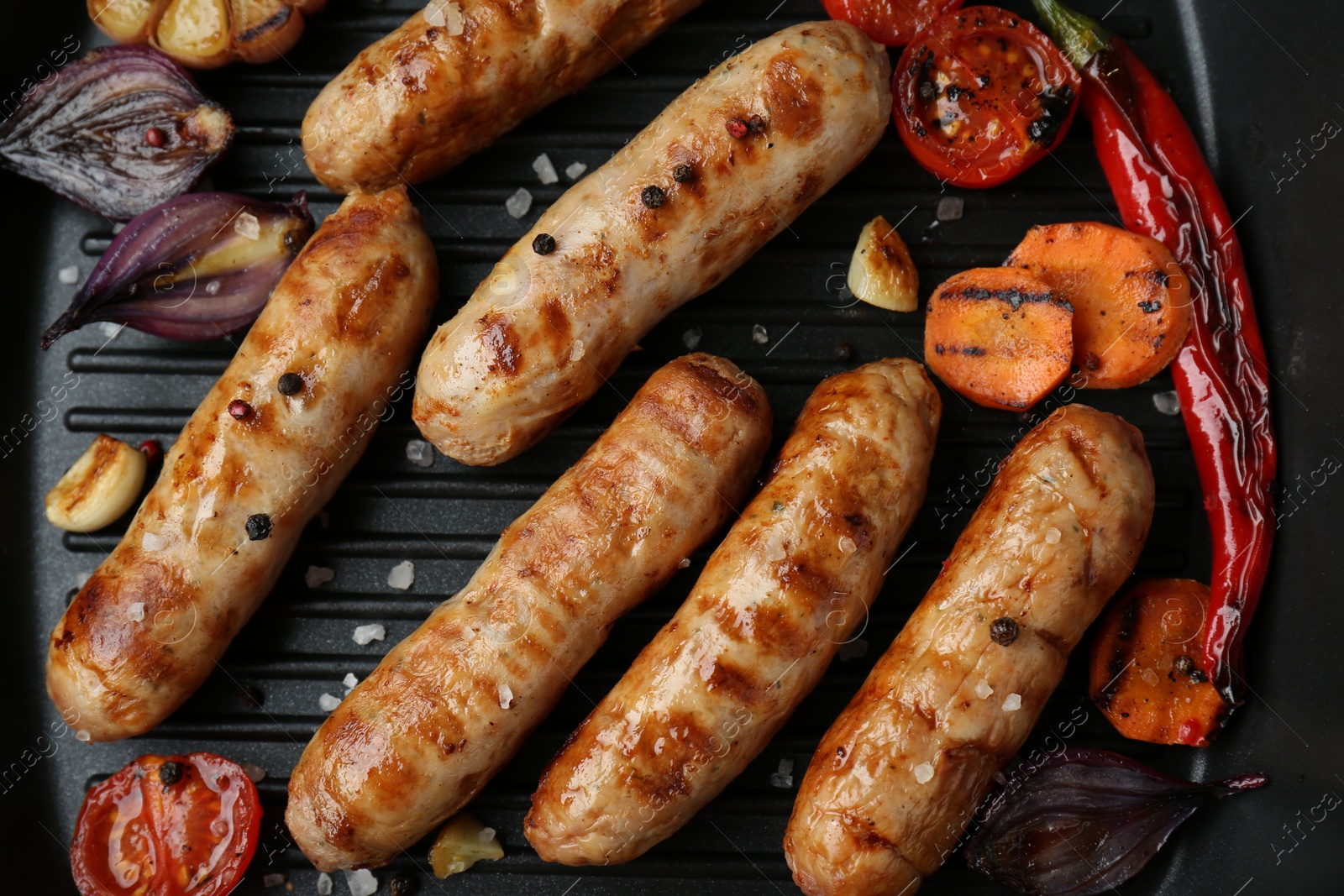 Photo of Tasty grilled sausages and vegetables in frying pan, flat lay
