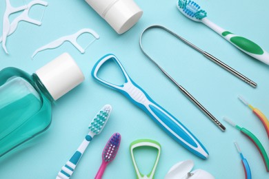 Photo of Tongue cleaners and other oral care products on light blue background, flat lay