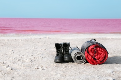 Photo of Set of camping equipment with sleeping bag on coast of pink lake