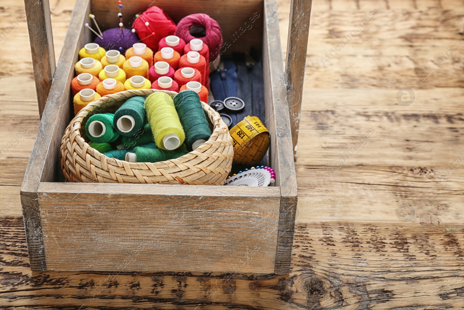 Photo of Box with color sewing threads on wooden background