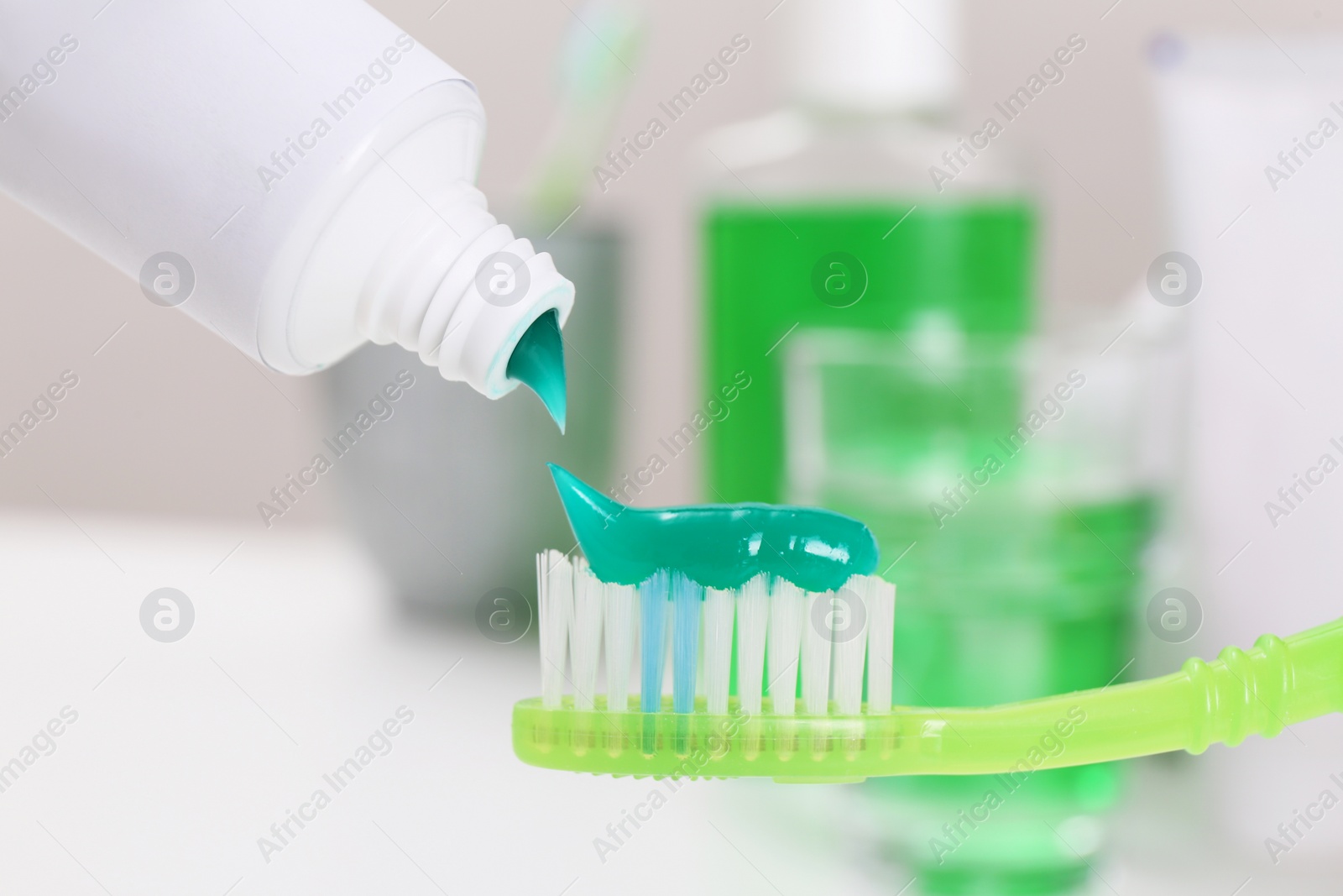 Photo of Applying paste on toothbrush near mouthwash, closeup