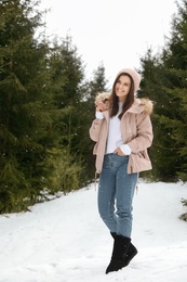 Young woman in snowy conifer forest. Winter vacation