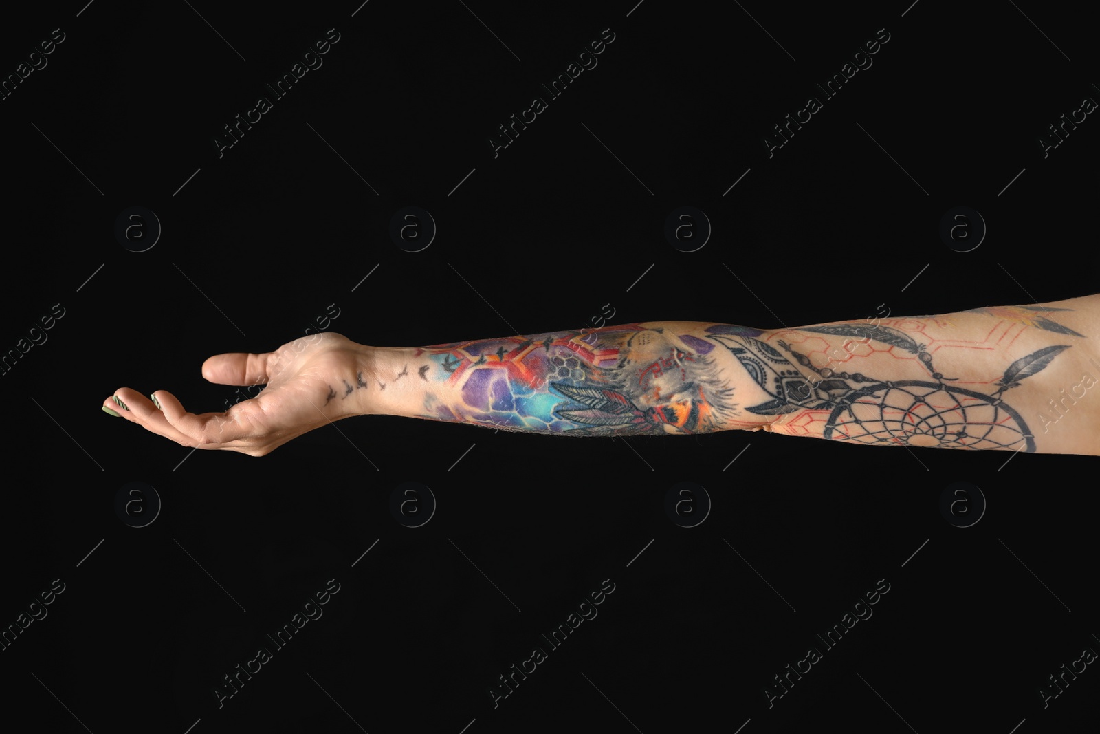 Photo of Woman with colorful tattoos on arm against black background, closeup