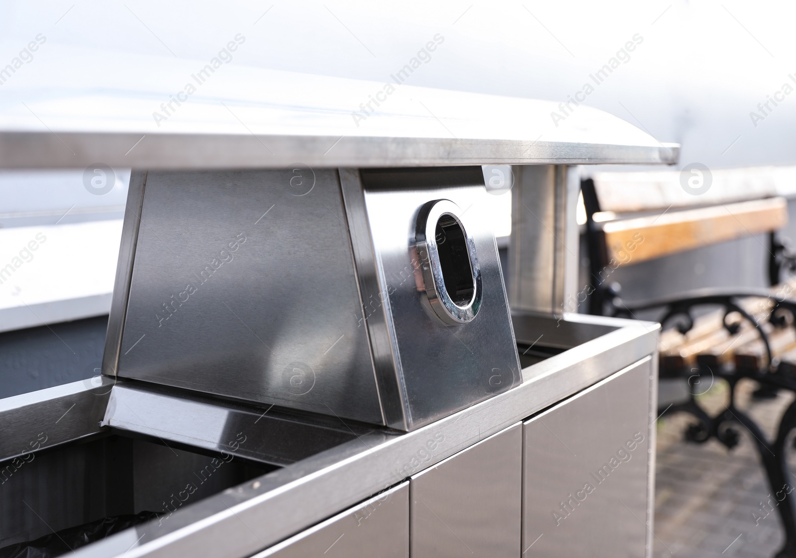 Photo of Modern metal recycling bin outdoors, closeup view. Space for text