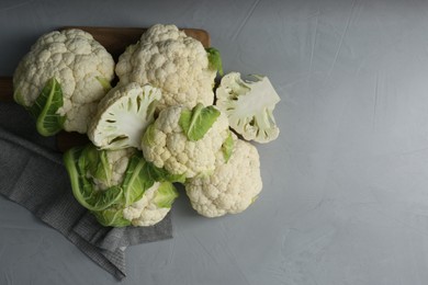 Photo of Fresh whole and cut cauliflowers on light grey table, top view. Space for text