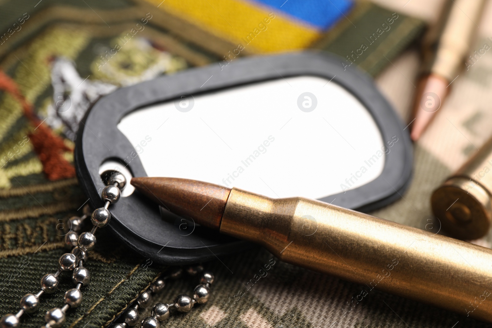 Photo of Bullets, military ID tag and Ukrainian patch on pixel camouflage, closeup