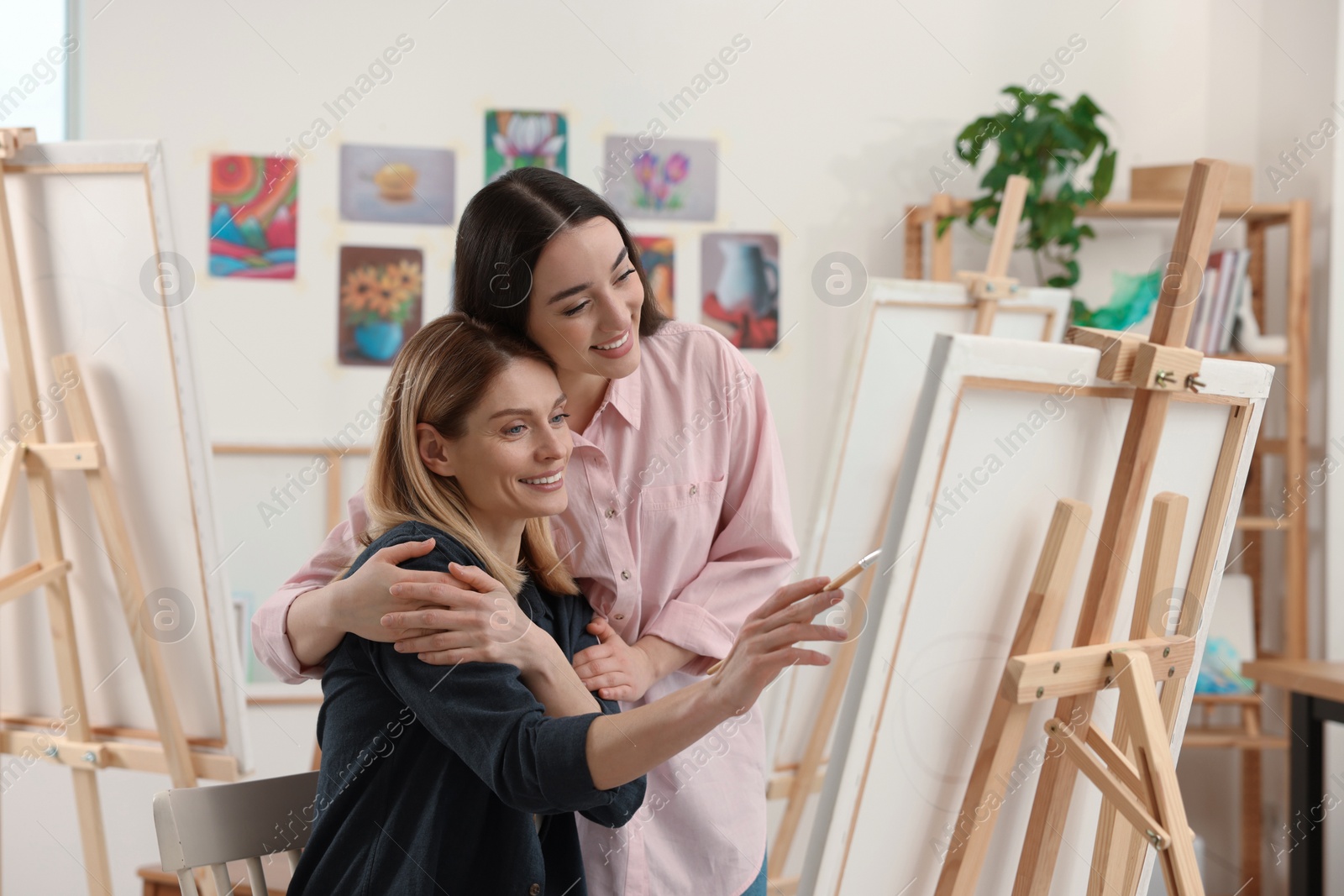 Photo of Artist teaching her student to paint in studio. Creative hobby