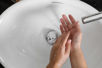 Woman washing hands with soap over sink in bathroom, top view. Space for text