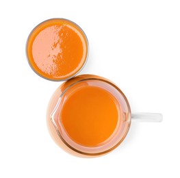 Photo of Glass and pitcher of fresh carrot juice on white background, top view