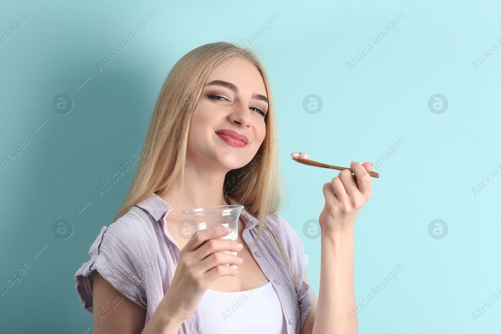 Photo of Young woman with yogurt on color background