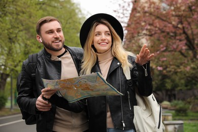 Photo of Couple of tourists with map planning trip on city street