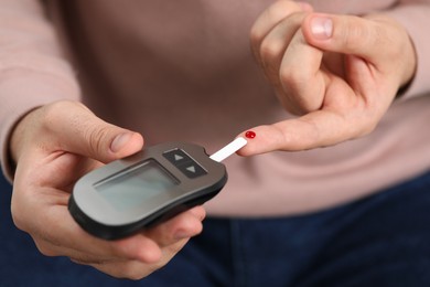 Photo of Diabetes test. Man checking blood sugar level with glucometer, closeup