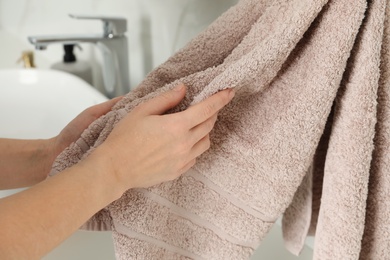 Photo of Woman wiping hands with towel in bathroom, closeup