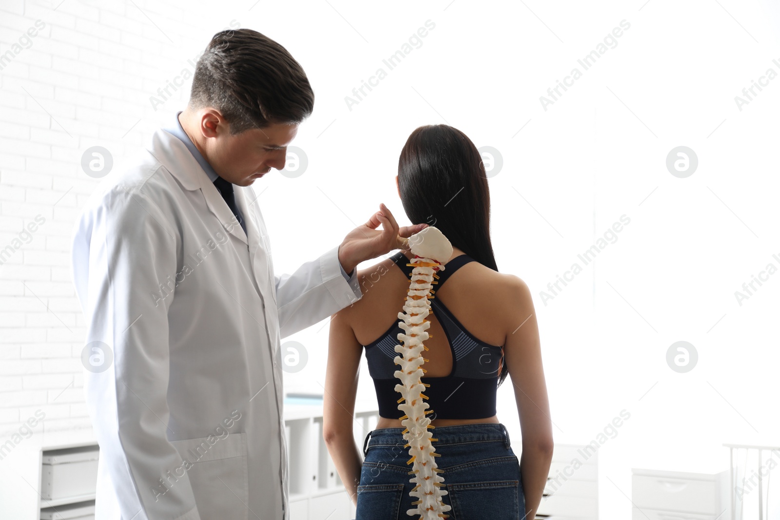 Photo of Professional orthopedist examining young woman in office