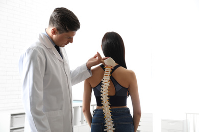 Professional orthopedist examining young woman in office