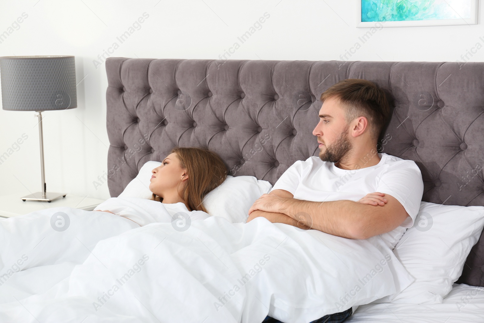 Photo of Upset young couple with relationship problems in bedroom