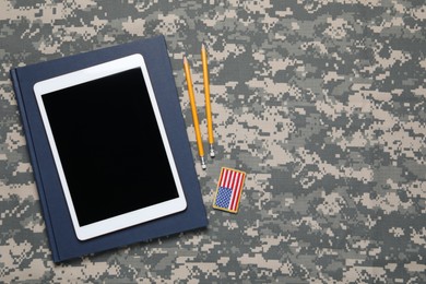 Notebook, tablet, pencils and patch on camouflage background, flat lay with space for text. Military education