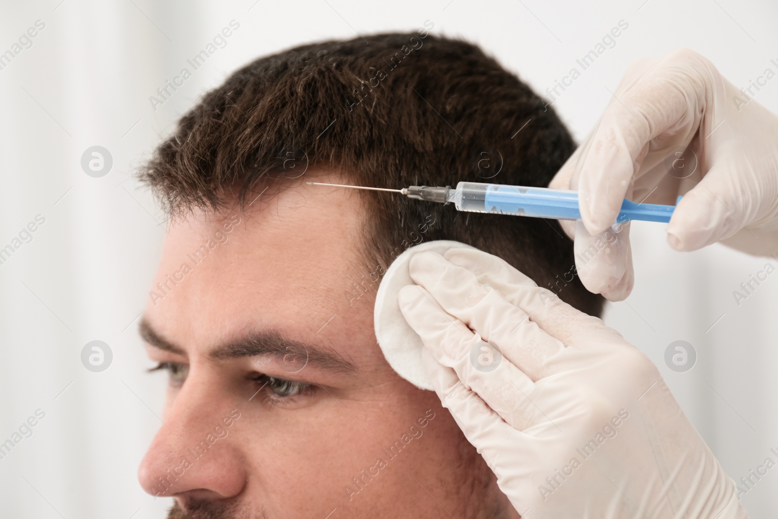 Photo of Man with hair loss problem receiving injection in salon, closeup