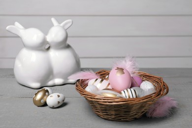 Photo of Wicker basket with festively decorated Easter eggs on grey wooden table