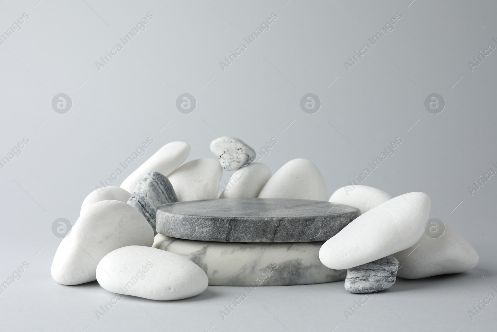 Photo of Presentation for product. Stone podium and pebbles on light grey background. Space for text