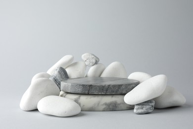 Photo of Presentation for product. Stone podium and pebbles on light grey background. Space for text