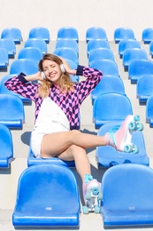 Happy girl with retro roller skates sitting on grandstand