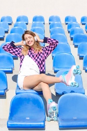 Photo of Happy girl with retro roller skates sitting on grandstand