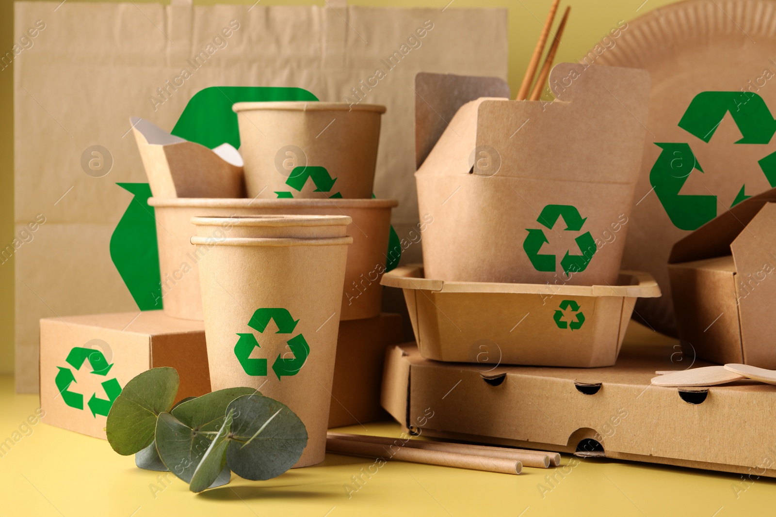 Image of Set of eco friendly food packaging with recycling symbols and eucalyptus branch on yellow background