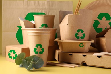 Set of eco friendly food packaging with recycling symbols and eucalyptus branch on yellow background