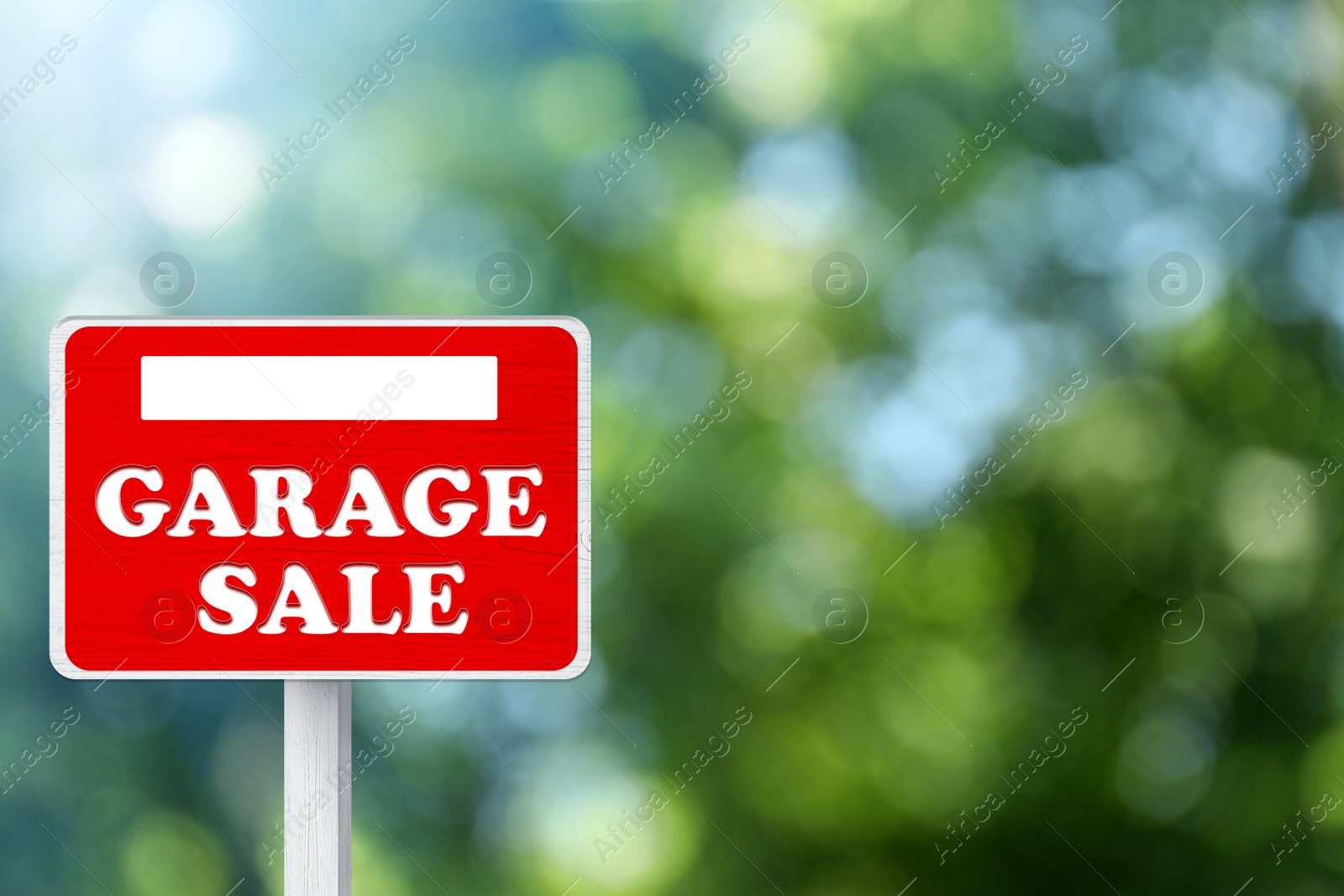 Image of Sign with phrase GARAGE SALE on blurred green background, bokeh effect