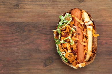 Fresh delicious hot dog on wooden table, top view. Space for text