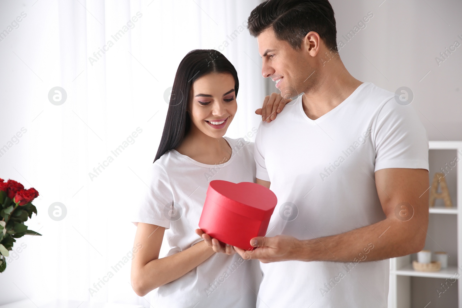 Photo of Lovely couple with gift box at home. Valentine's day celebration