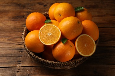 Photo of Many ripe oranges and green leaves on wooden table