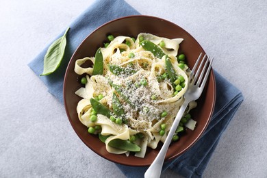 Photo of Delicious pasta with green peas and cheese served on grey table