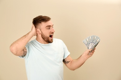 Photo of Portrait of emotional young man with money on color background