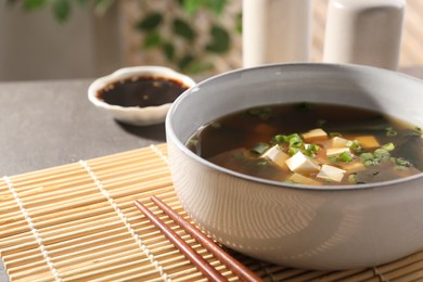 Bowl of delicious miso soup with tofu and chopsticks on table, closeup. Space for text