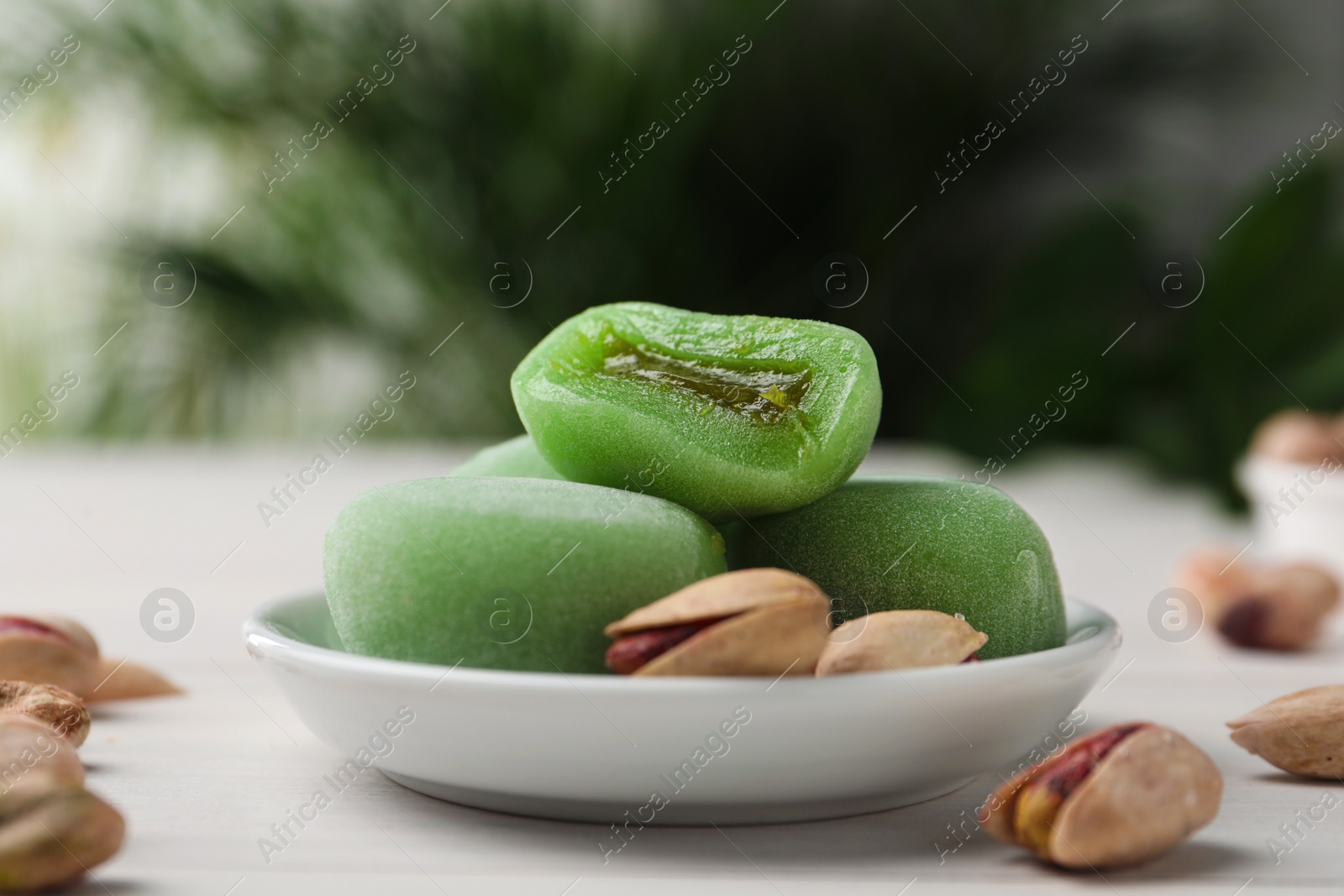 Photo of Delicious mochi and pistachios on white wooden table, closeup. Traditional Japanese dessert