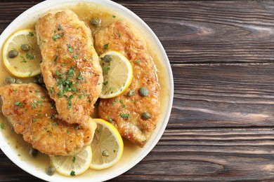 Photo of Delicious chicken piccata on wooden table, top view. Space for text