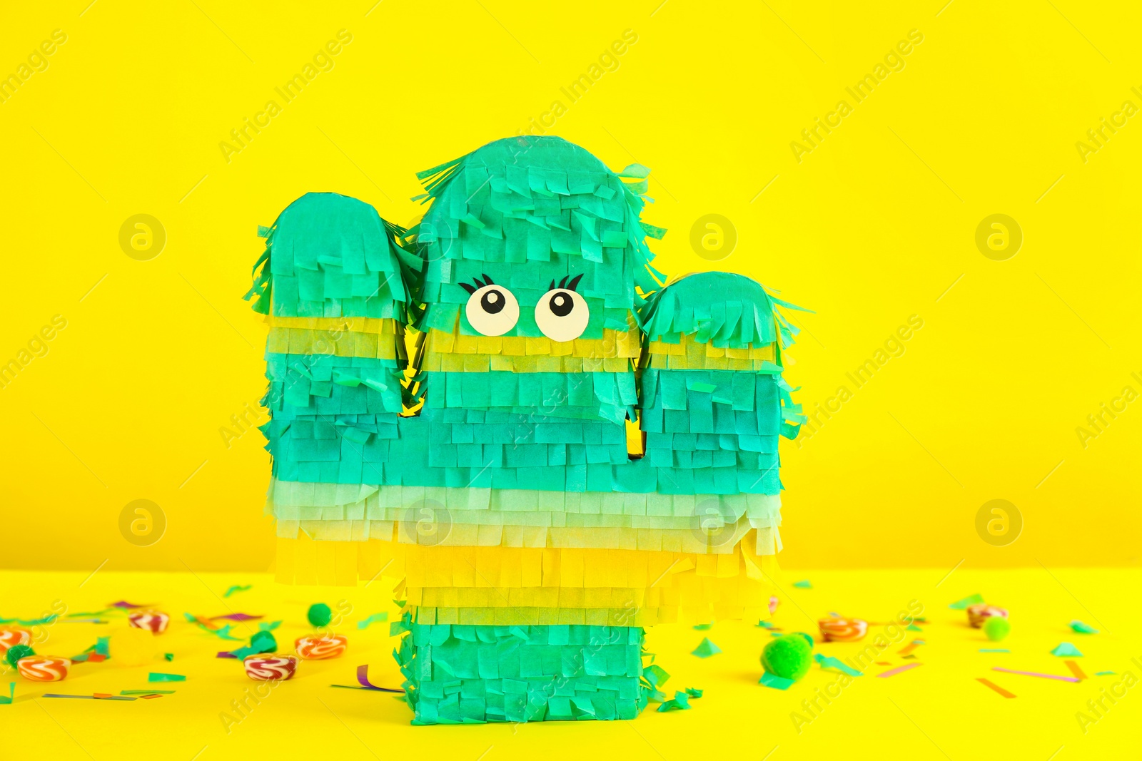 Photo of Cactus shaped pinata and decor on yellow background