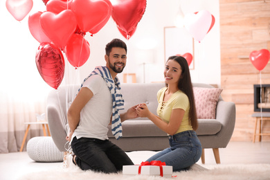 Happy young couple with heart shaped balloons in living room. Valentine's day celebration