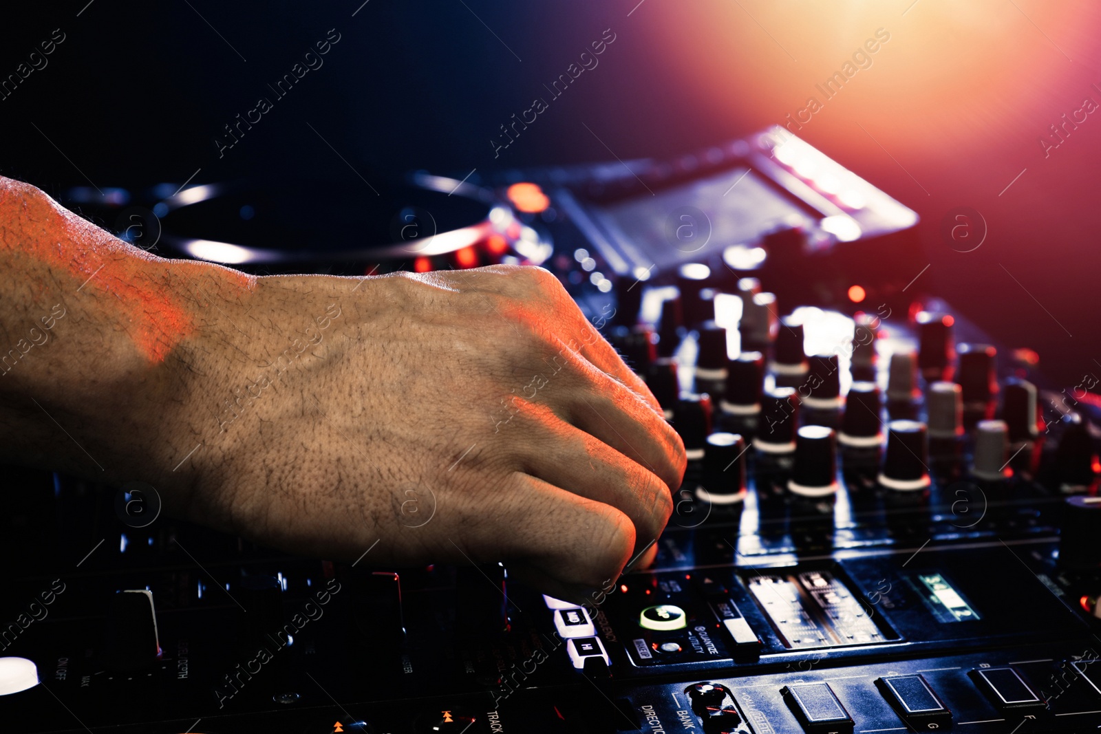 Photo of DJ creating music on modern console mixer in night club, closeup