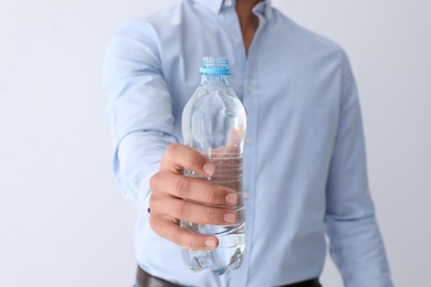 Man holding bottle of pure water on white background, closeup