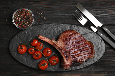 Delicious beef steak served on black wooden table, flat lay