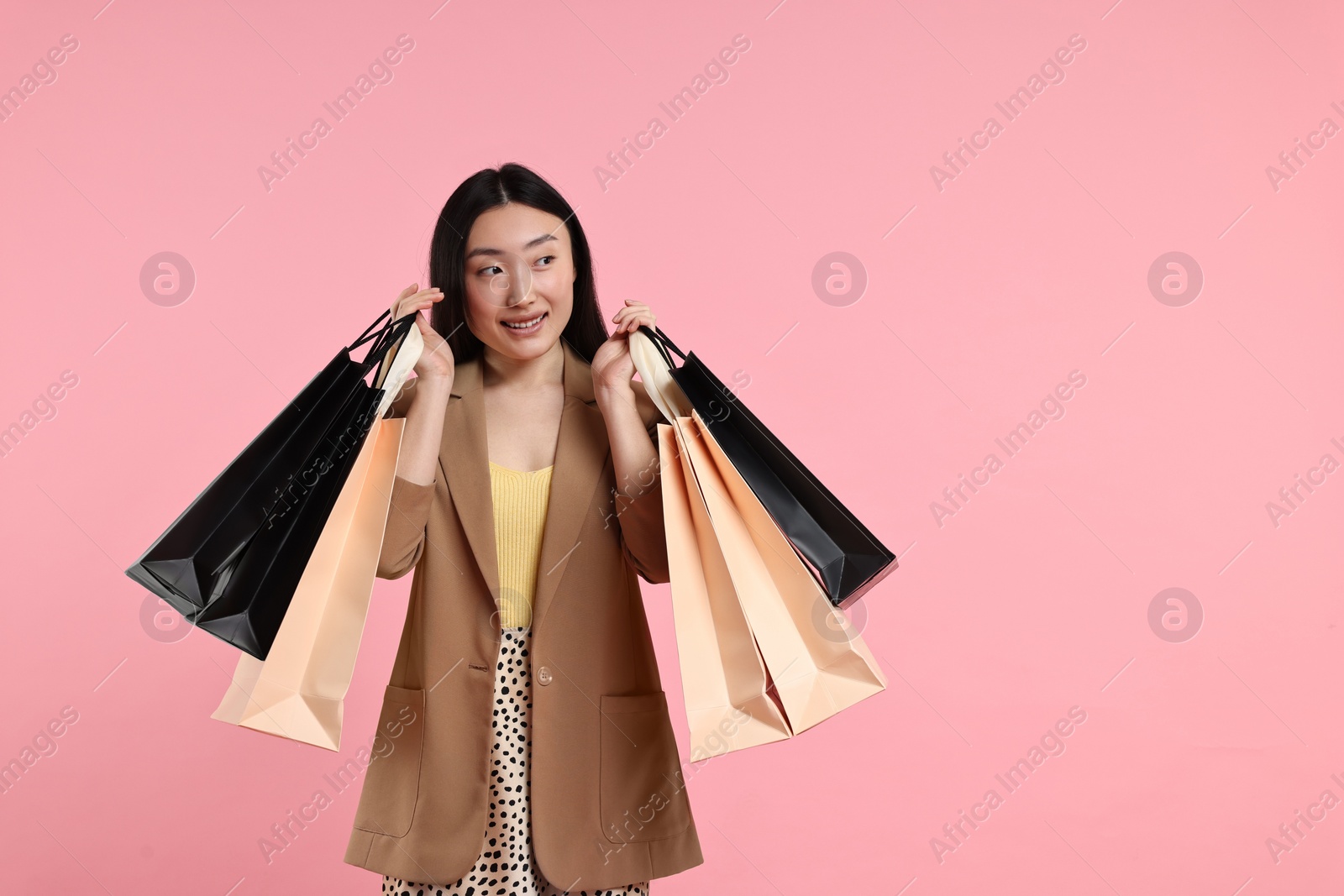 Photo of Smiling woman with shopping bags on pink background. Space for text