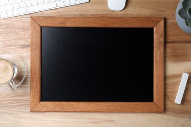 Photo of Clean small black chalkboard, coffee and chalk on wooden table, flat lay