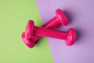 Photo of Bright dumbbells on color background, flat lay. Home fitness