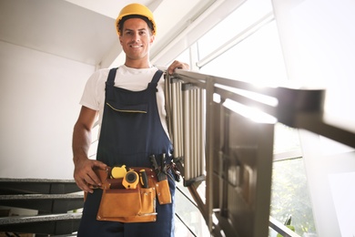Photo of Professional builder carrying metal ladder down stairs